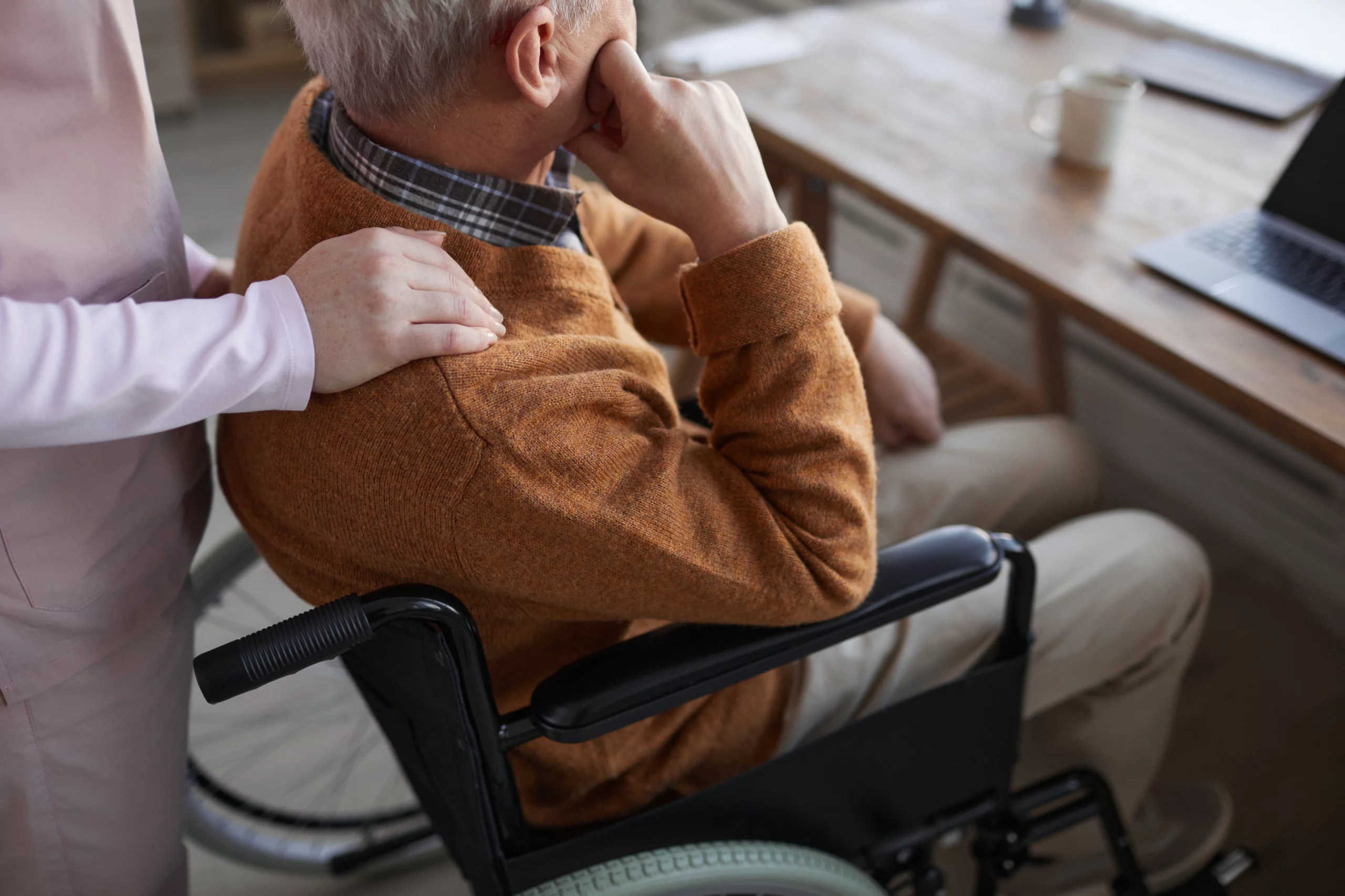Elderly person in wheelchair comforted by supportive hand, illustrating adult guardianship care in Florida.