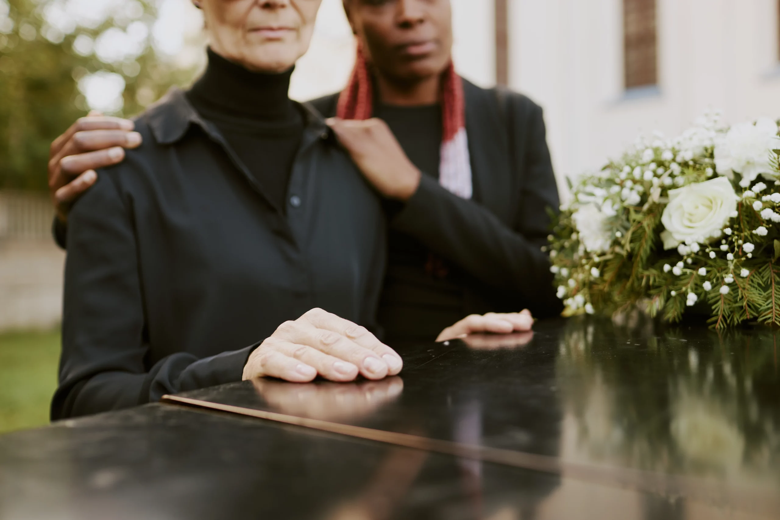 Grieving family standing beside casket with white flowers, symbolizing estate matters after death and how bank accounts in Florida may be frozen or transferred to beneficiaries or probate depending on ownership and designation.