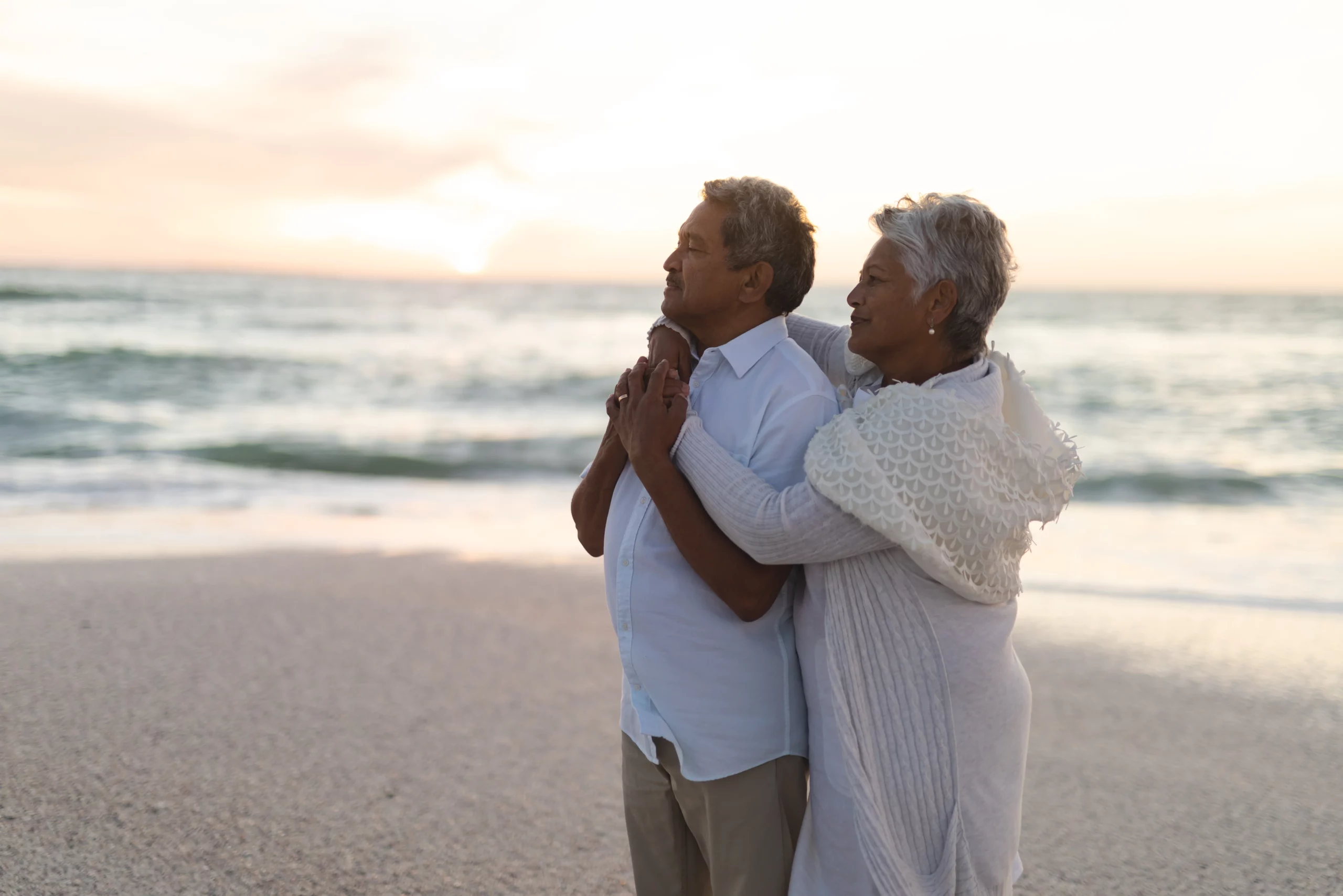 Elderly couple embracing on beach at sunset, symbolizing Florida estate planning where a trust may already control assets but a will is still needed to cover remaining property and ensure full distribution wishes are legally carried out.