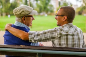 Man and older guardian sharing supportive conversation on park bench, symbolizing situations where guardianship may be necessary when an adult or minor cannot fully manage personal care or decision-making without assistance.